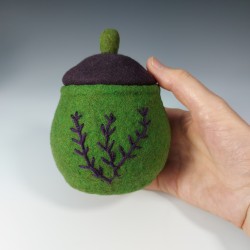 Small green felted pot with embroidery and a purple lid.